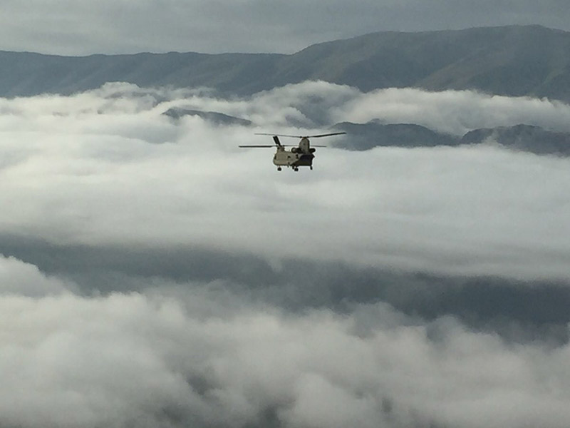 military helicopter flying over clouds